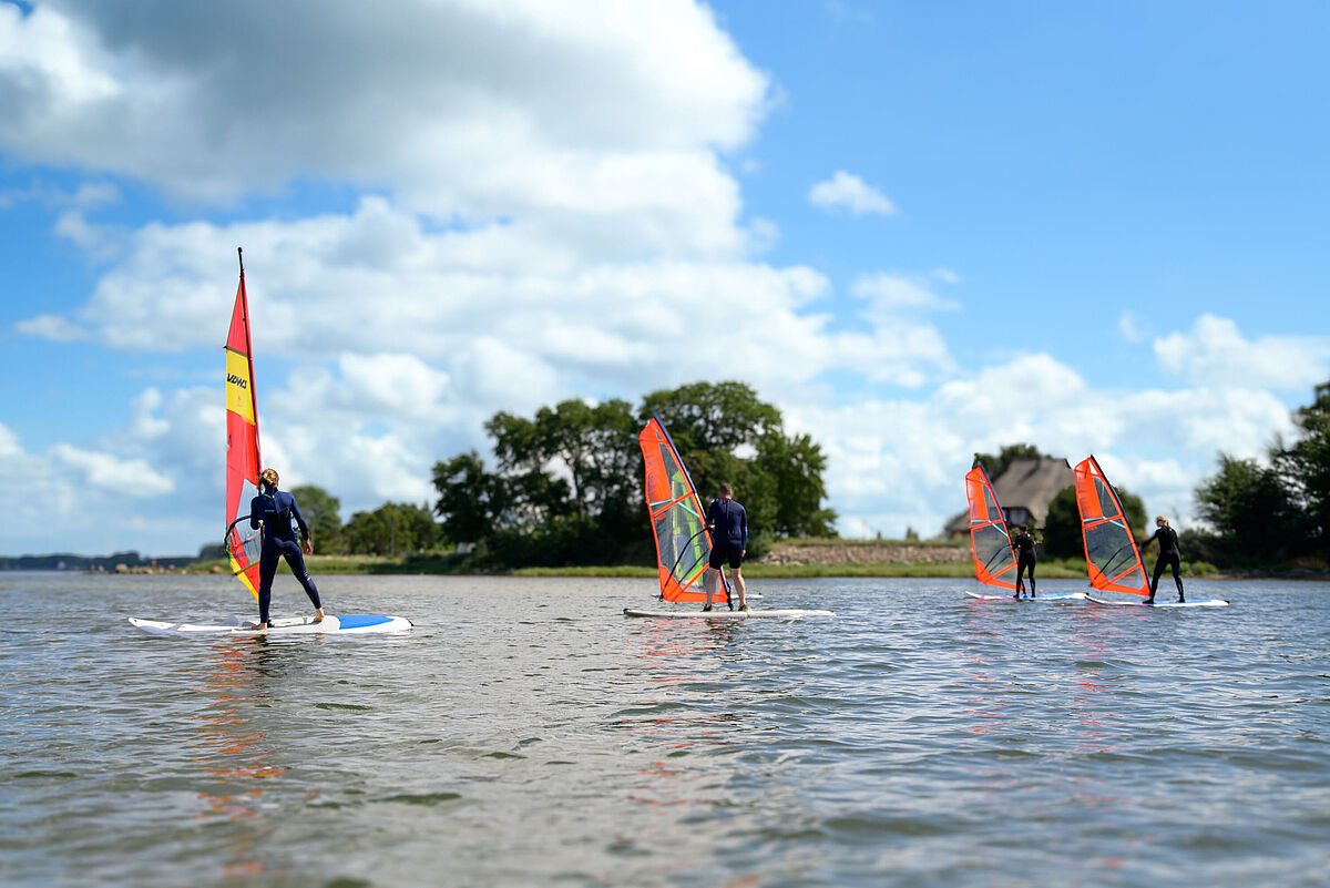 Auf dem Wasser Windsurfen mehrere Menschen bei blauem Himmel.